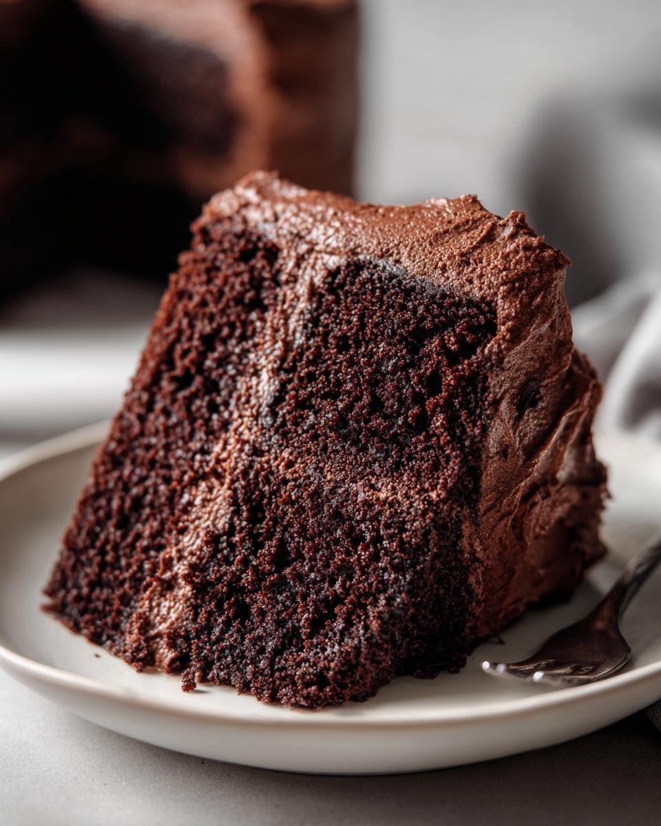 A slice of Guinness Chocolate Layer Cake on a white plate, showing the moist texture and frosting.