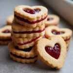 A stack of delicious Heart-Shaped Linzer Cookies filled with raspberry jam, perfect for a quick treat.