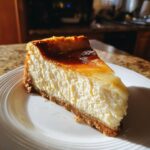 A slice of Irish Cream Cheesecake on a white plate, showing the creamy filling and crust.