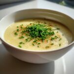 Close-up of a bowl of creamy Irish Potato and Leek Soup garnished with chives.