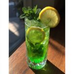 A tall glass of Leprechaun Lemonade with mint, garnished with lemon slices and fresh mint sprigs.