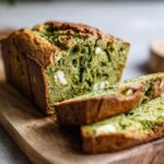 Close-up of sliced Matcha White Chocolate Loaf Cake on a wooden board, showing the texture and white chocolate.
