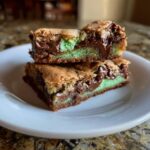 Two stacked Mint Chocolate Chip Cookie Bars on a white plate, showing layers of mint and chocolate.