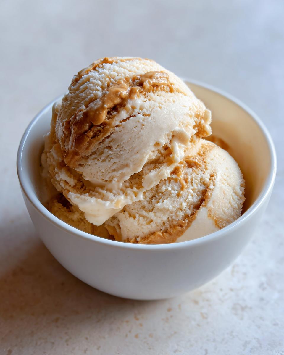 Close-up of Peanut Butter Banana Frozen Yogurt Treats in a white bowl, drizzled with peanut butter.
