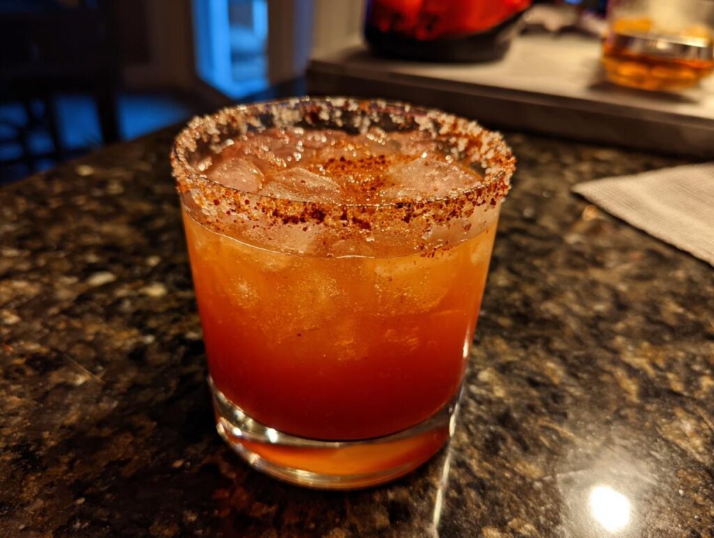Close-up of a Spicy Valentine's Day Margarita cocktail with a chili-salt rim and ice.