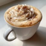 A warm Vanilla Chai Valentine’s Latte in a white mug, topped with whipped cream and cinnamon.