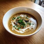 A bowl of creamy Wild Mushroom Valentine’s Day Soup garnished with fresh parsley and cream.