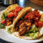 Close-up of two Easy Blackened Chicken Tacos with lettuce, salsa, and tomatoes.