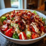 A vibrant BLT Quinoa Bowl with crispy bacon, tomatoes, lettuce, and a creamy dressing.