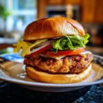 Close-up of a fully assembled crispy air fryer chicken burger with toppings on a bun.