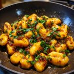 Close-up of Gnocchi with Basil Brown Butter in a pan, garnished with fresh basil.