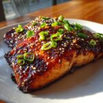 Close-up of a perfectly cooked Miso Glazed Salmon fillet, garnished with sesame seeds and green onions.