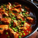 Close-up of a flavorful Romanian Chicken & Pea Stew with chicken pieces and green peas.