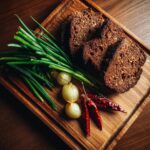 Wooden platter with rye bread, green onions, onions, and chili peppers, perfect for Spring Dinner Party Menu Ideas.