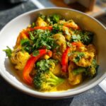 Close-up of a bowl of Thai Yellow Curry with Chicken, broccoli, and red bell peppers.