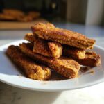 Stack of Apple Cinnamon Crunchy Dog Treats on a white plate, close-up view.