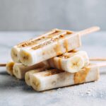 Close-up of stacked Banana Peanut Butter Frozen Dog Bites, drizzled with peanut butter.