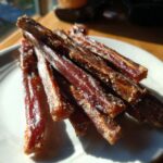 Close-up of a pile of Beef & Apple Healthy Dog Chew Sticks on a white plate.