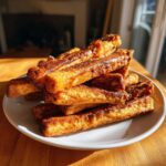 A stack of golden brown Beef and Spinach Crunchy Dog Sticks on a white plate.