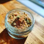 Close-up of a jar filled with homemade Salmon Oat Topper Sprinkle for Dogs.