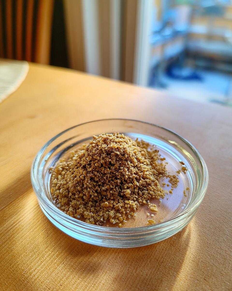 Close-up of Homemade Salmon Oat Topper Sprinkle for dogs in a glass dish.