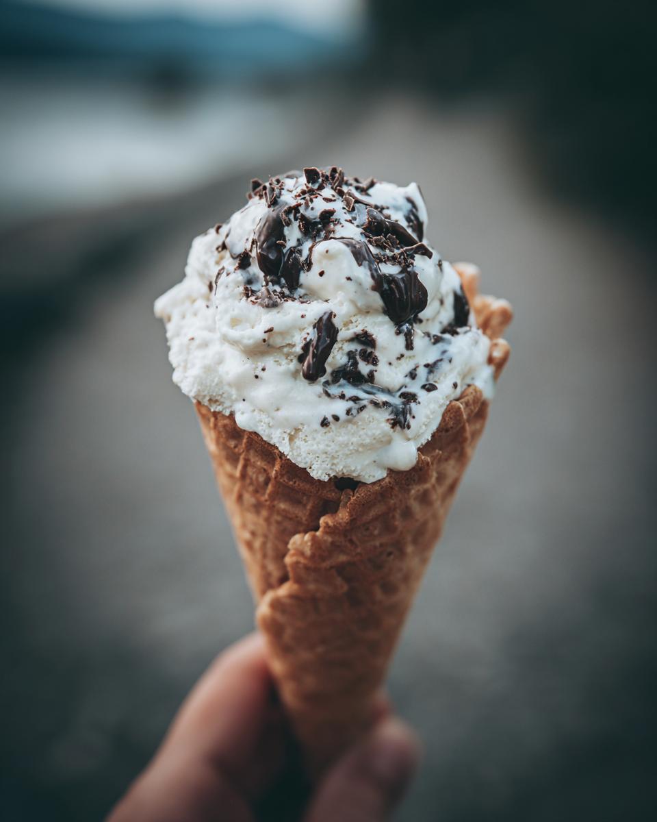Close-up of an ice cream cone with white ice cream and chocolate shavings. This recipe is for 2-Ingredient Dog Ice Cream.