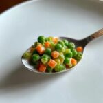 Close-up of Pea and Carrot Homemade Dog Dip on a spoon, ready to serve.