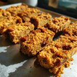 Close-up of freshly baked Peanut Butter Bacon Dog Treats on a baking sheet, ready for pups.