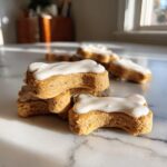 Close-up of a stack of bone-shaped peanut butter dog cookies with white icing.