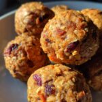 Close-up of several Pumpkin Peanut Butter Dog Energy Balls on a plate, showing texture and ingredients.