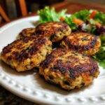 Close-up of cooked Salmon Spinach Dog Patties served on a white plate with salad.