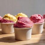 Close-up of strawberry banana frozen yogurt dog cups in paper cups, perfect for dogs.