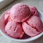Close-up of a bowl filled with several scoops of strawberry yogurt dog ice cream.