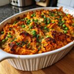 Overhead shot of a baked Sweet Potato and Pea Puppy Mash Topper in a white dish, garnished with peas and herbs.