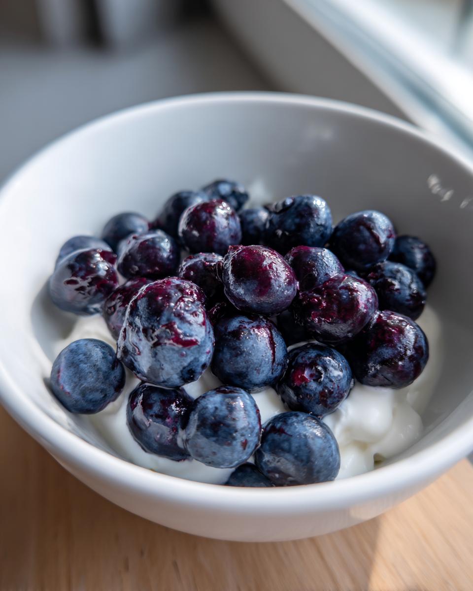 Close-up of blueberries on top of yogurt in a white bowl, for Yogurt Blueberry Frozen Dog Drops.
